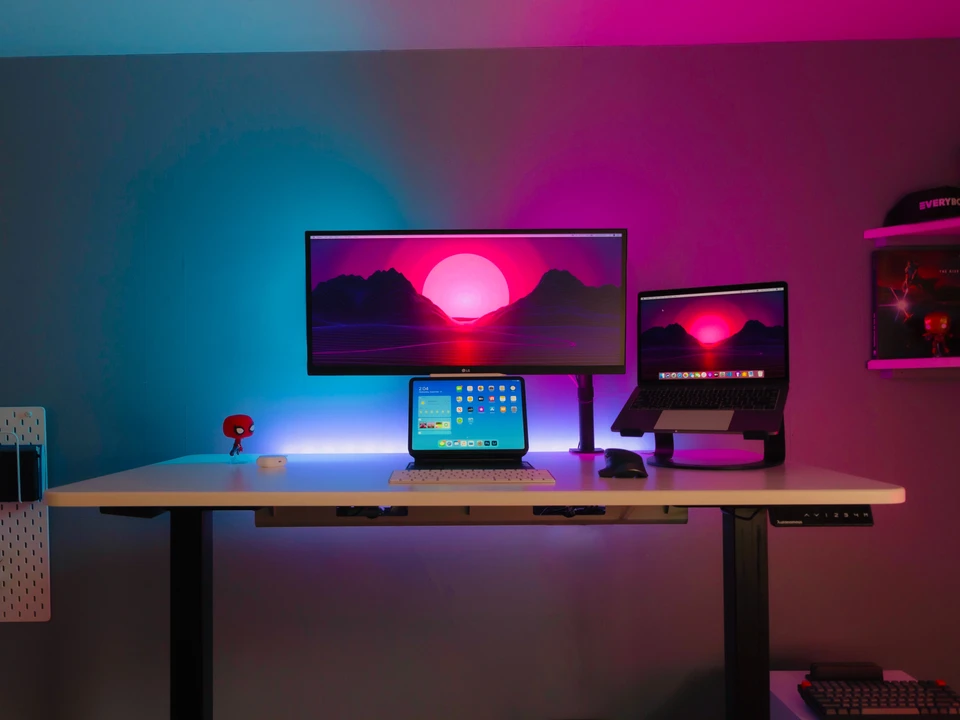 A desk with a computer monitor, laptop, and tablet